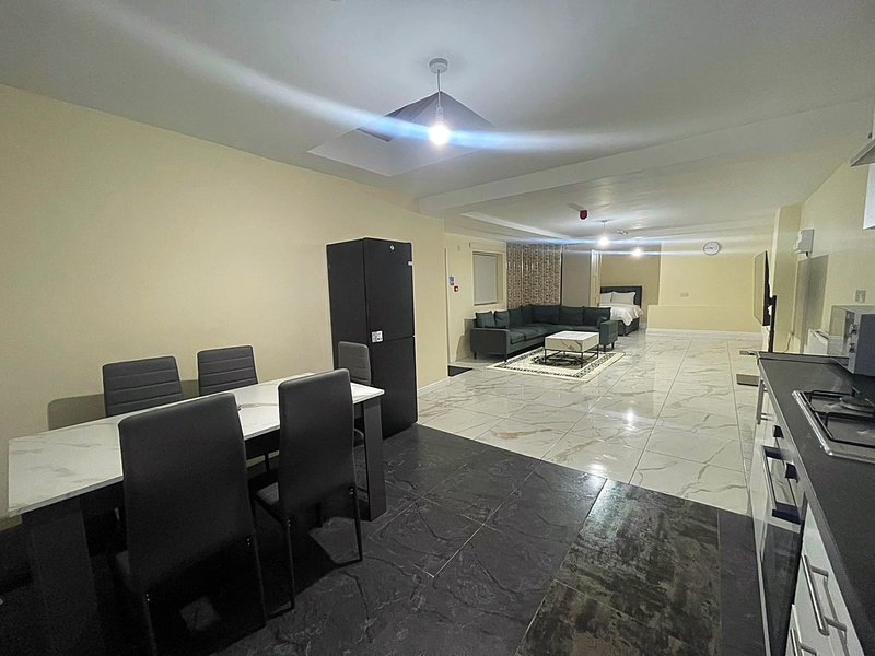 Open-plan living space with dining table, kitchen area, and lounge seating on polished floor