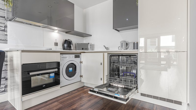 Modern kitchen with white cabinetry, built-in appliances, and wooden flooring