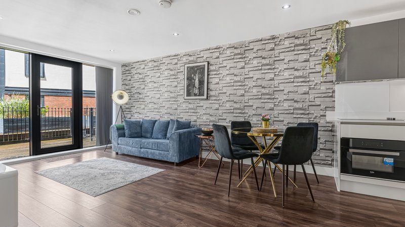 Modern open-plan living room with blue sofa, dining table, brick accent wall and fireplace