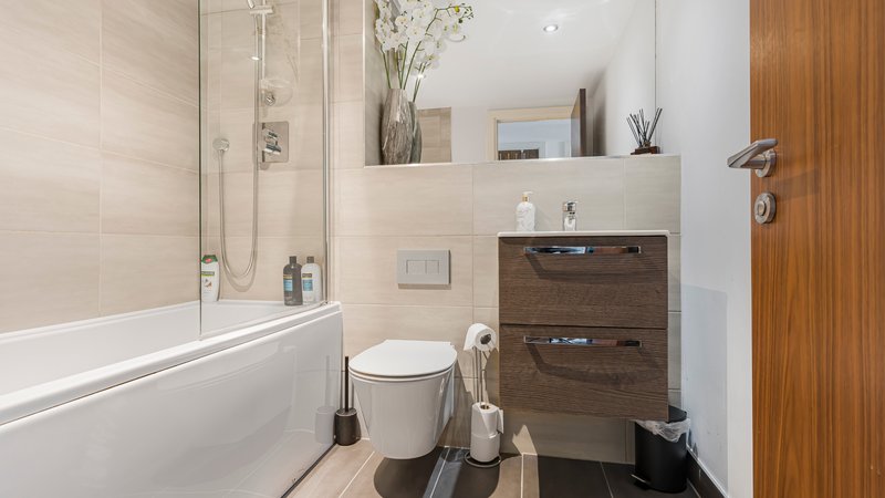 Modern bathroom with bathtub, toilet, wooden vanity and shower enclosure