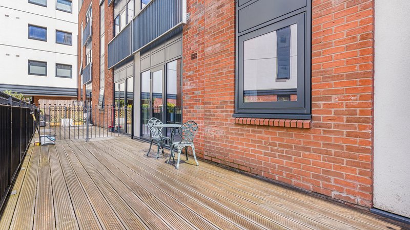 Modern brick building exterior with wooden deck terrace and seating area