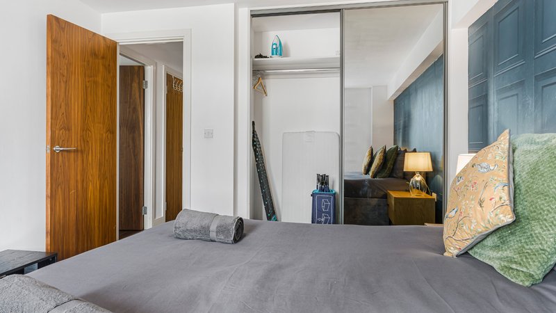 Bedroom with double bed, wooden doors, wardrobe and bedside lamp
