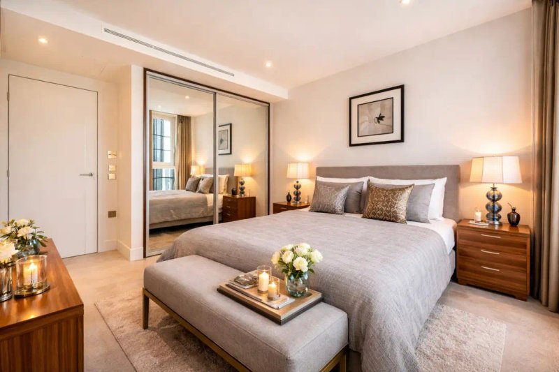 Modern bedroom with double bed, mirrored wardrobe, bedside lamps and wooden furniture