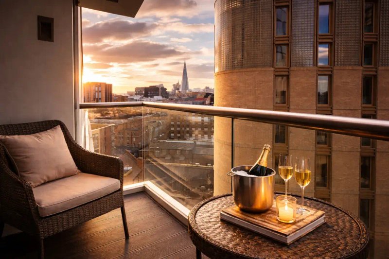 Balcony seating area with chair, table, champagne bucket and city skyline view at sunset