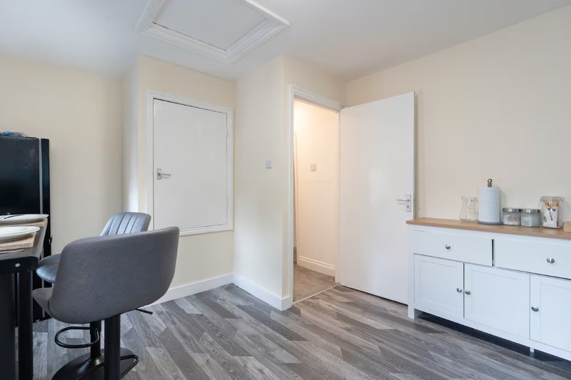 Modern bedroom with desk, chair, white cabinetry, and wood-look flooring