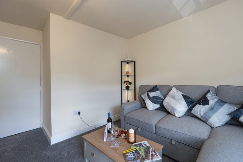 Living room with grey sofa, wooden coffee table, pendant lamp and white walls