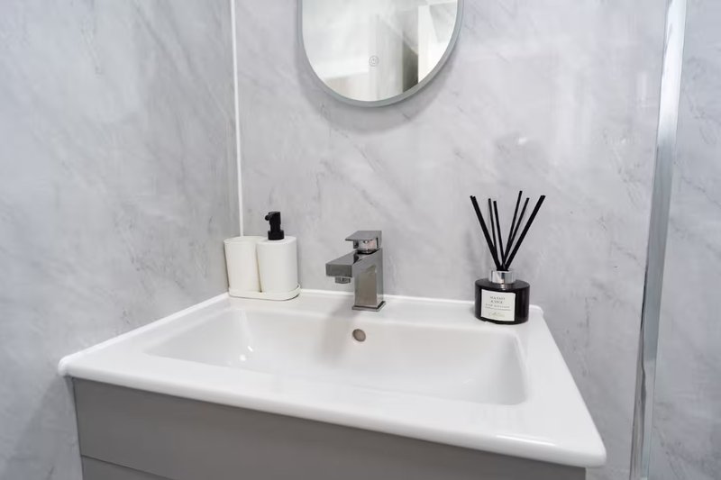 Modern bathroom sink with mirror, soap dispenser, and decorative reed diffuser