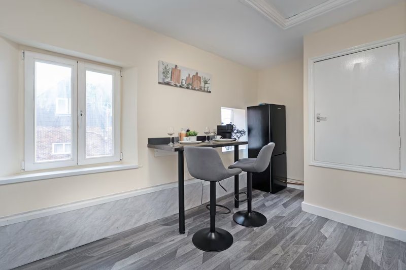 Modern home office with desk, chair, computer monitor, and city view from windows