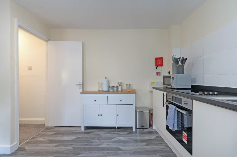 Modern kitchen with white cabinetry, black gas range, and wooden countertop