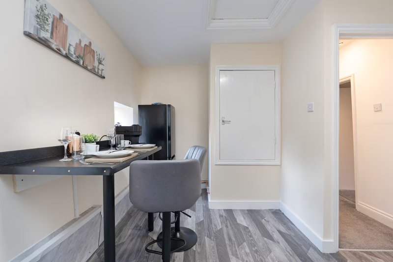 Modern home office with black desk, gray chair, black kettle and white walls