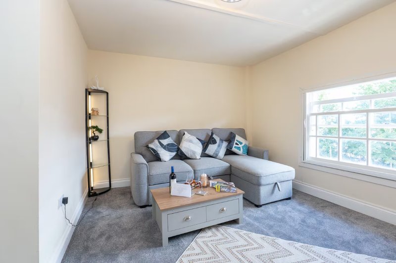 Bright living room with grey sectional sofa, wooden coffee table, floor lamp and large window