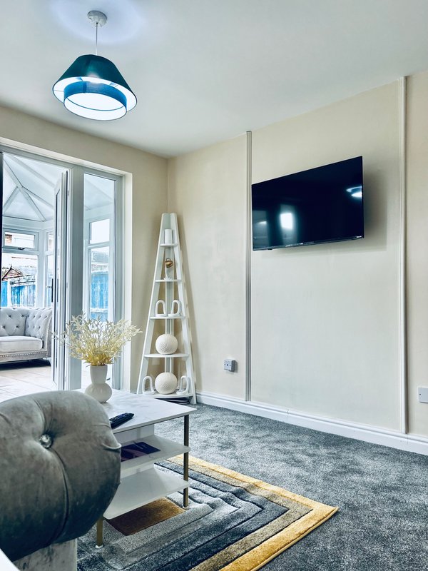 Modern living room with mounted TV, pendant light, grey sofa and decorative shelving