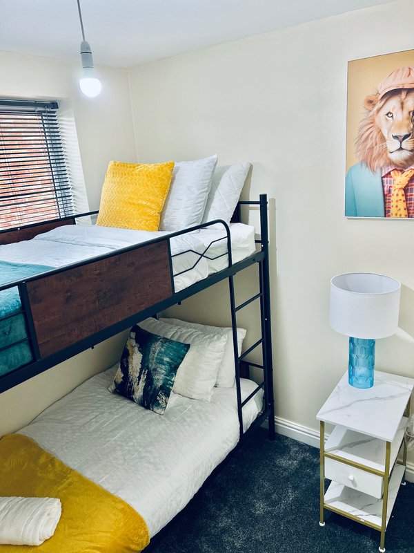 Shared bedroom with bunk beds, yellow cushions, pendant light, and wall art