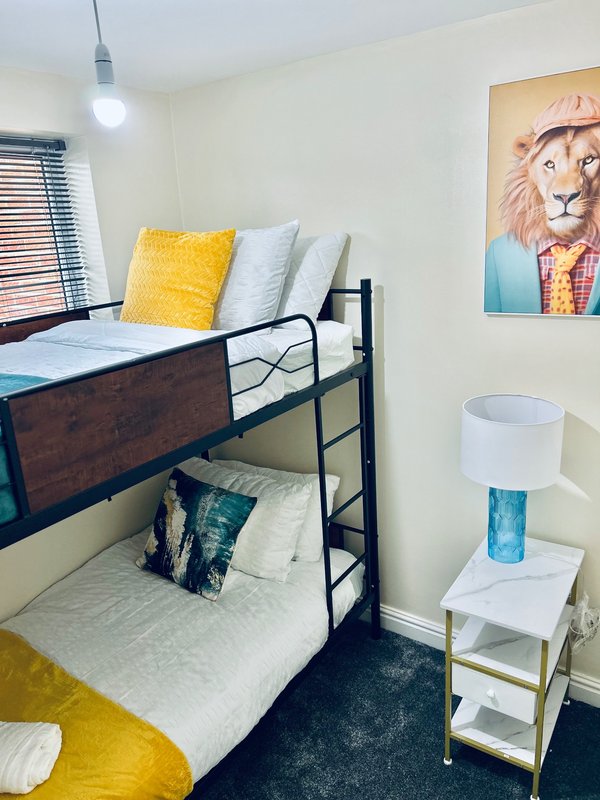 Bright bedroom with bunk beds, yellow cushions, pendant light, and wall art