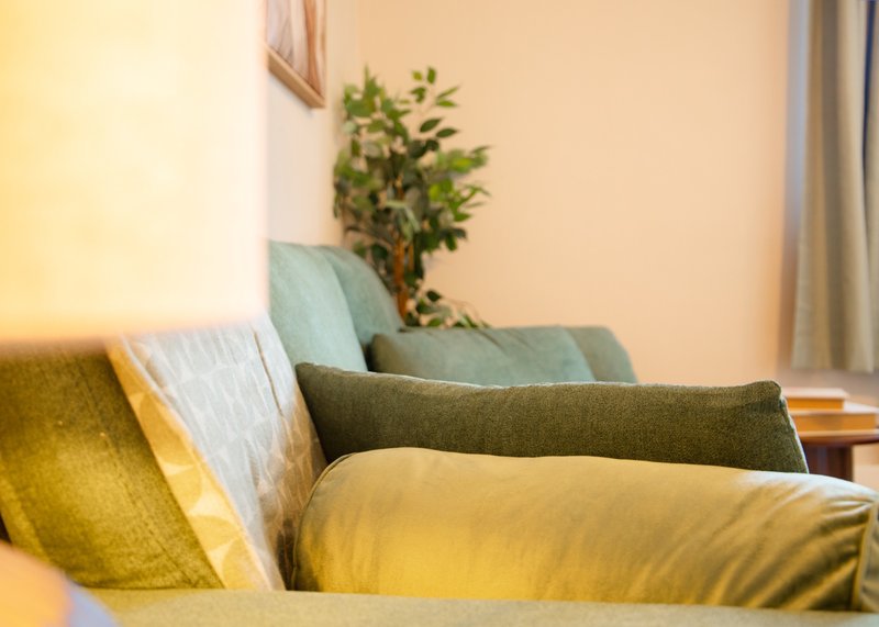 Living room corner with sofa, colorful cushions, potted plant, and warm lighting