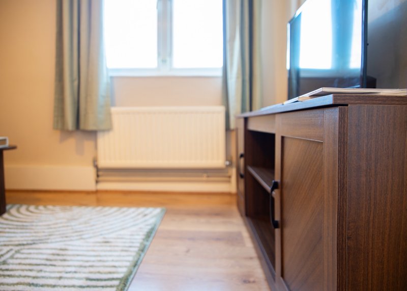 Modern bedroom with wooden furniture, window with curtains, and light wood flooring