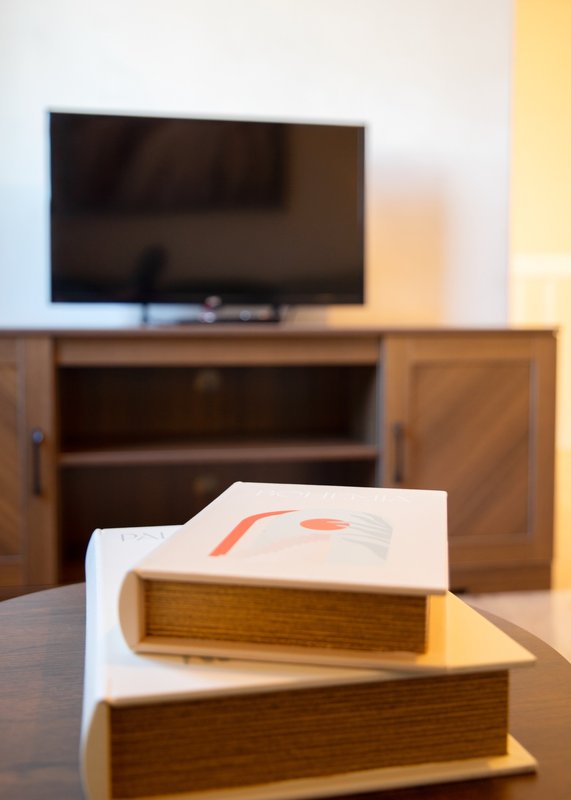 Living room with wooden TV stand, flat-screen TV, and stacked books on table