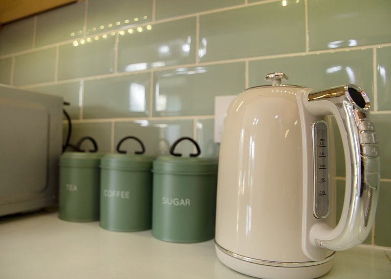 Modern kitchen countertop with cream kettle, green storage canisters and pendant lighting