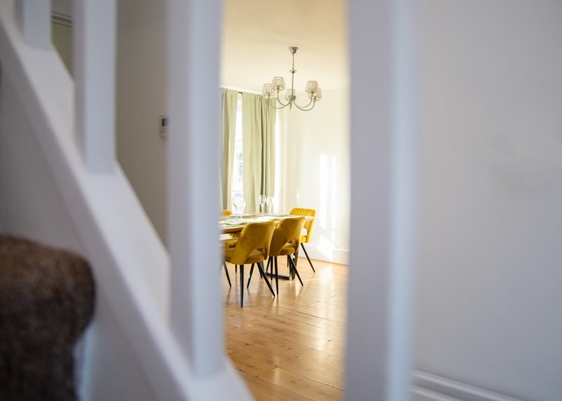 Bright hallway with view into dining room with yellow chairs and chandelier