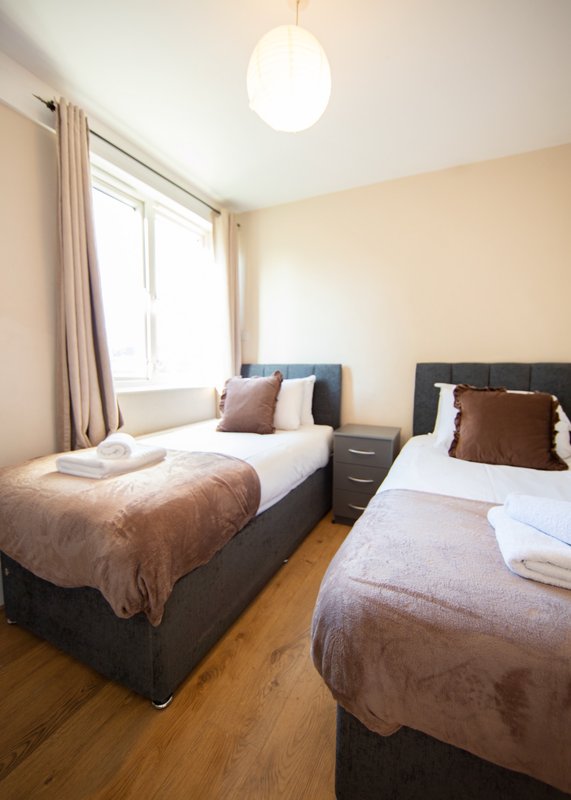 Bright twin bedroom with two single beds, wooden floor, pendant light and window