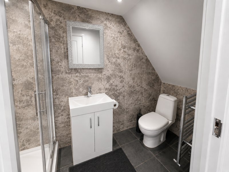 Modern bathroom with shower cubicle, white vanity unit, toilet, and heated towel rail