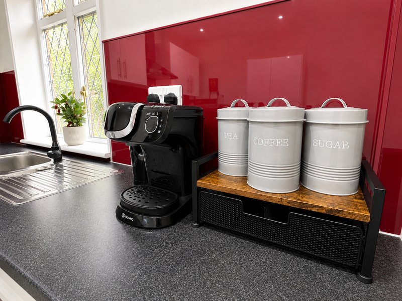 Modern kitchen with red backsplash, coffee machine, and labeled storage containers on counter