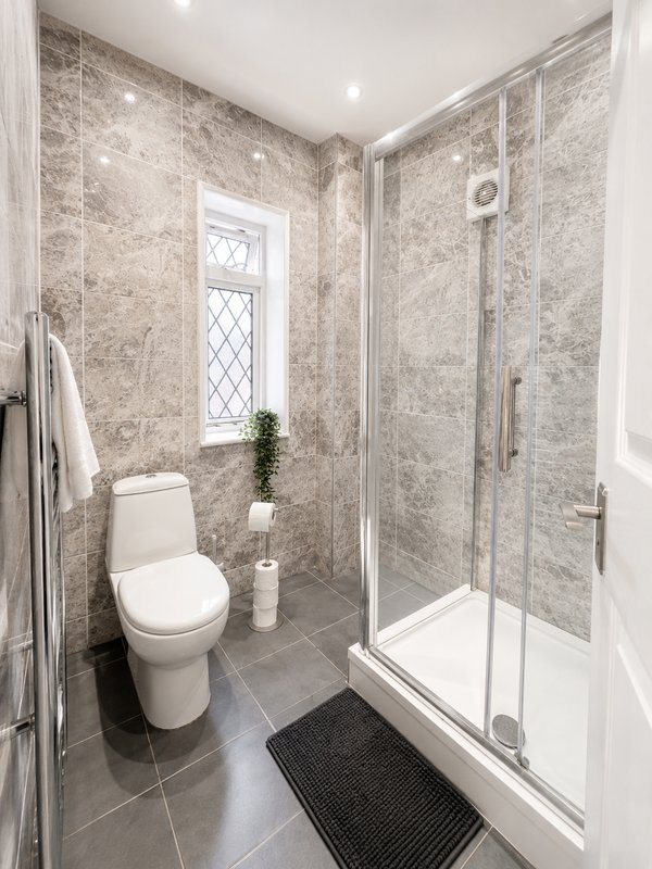 Modern bathroom with shower enclosure, toilet, heated towel rail, and window