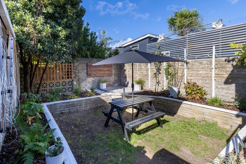 Enclosed backyard with patio table, bench seating, lawn, and stone walls