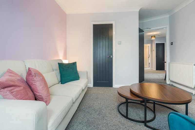 Modern living room with cream sofa, pink cushions, wooden coffee table and teal accents