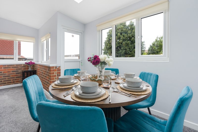 Bright dining room with round table, blue upholstered chairs, place settings and flowers