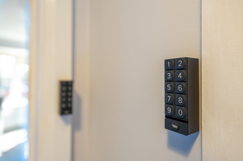 Digital keypad lock mounted on white door frame with numbered buttons