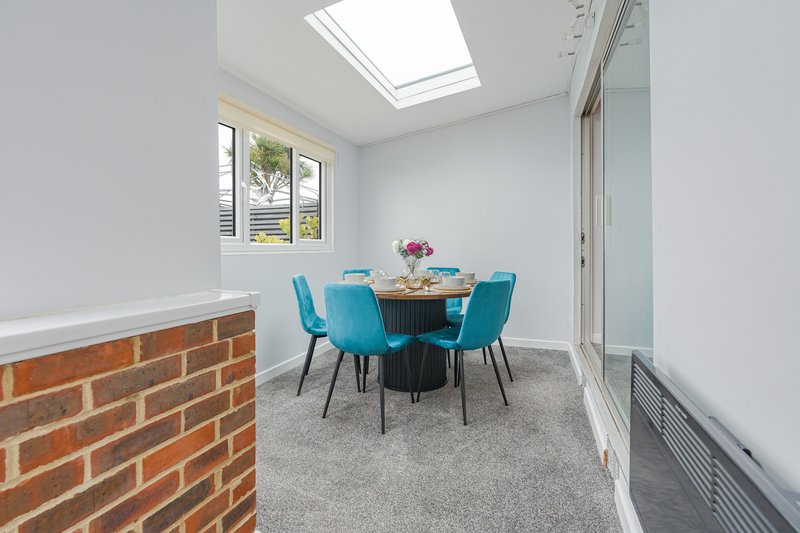 Modern dining area with blue chairs, round table, skylight and brick feature wall