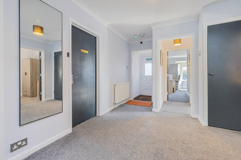 Modern hallway with multiple doors, mirrored wall panel, and carpet flooring