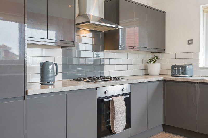 Modern kitchen with grey cabinetry, white subway tile splashback, gas hob and stainless steel extractor hood