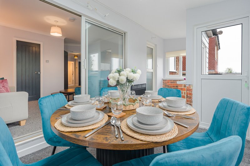 Dining room with round wooden table, blue upholstered chairs, place settings and white flowers