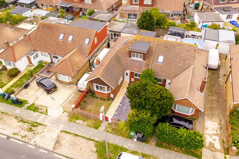 Aerial view of brick terraced houses with driveways, gardens, and surrounding residential street