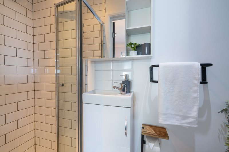 Modern bathroom with shower enclosure, white vanity sink, mirror and towel rail