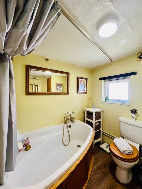 Bright yellow bathroom with bathtub, toilet, mirror and shower curtain