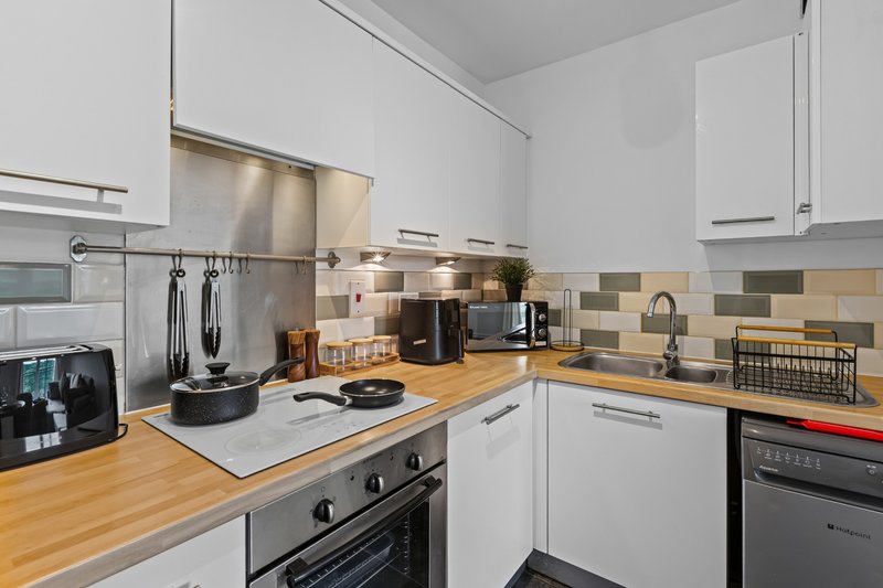Modern kitchen with white cabinetry, wooden countertops, stainless steel appliances and tiled backsplash