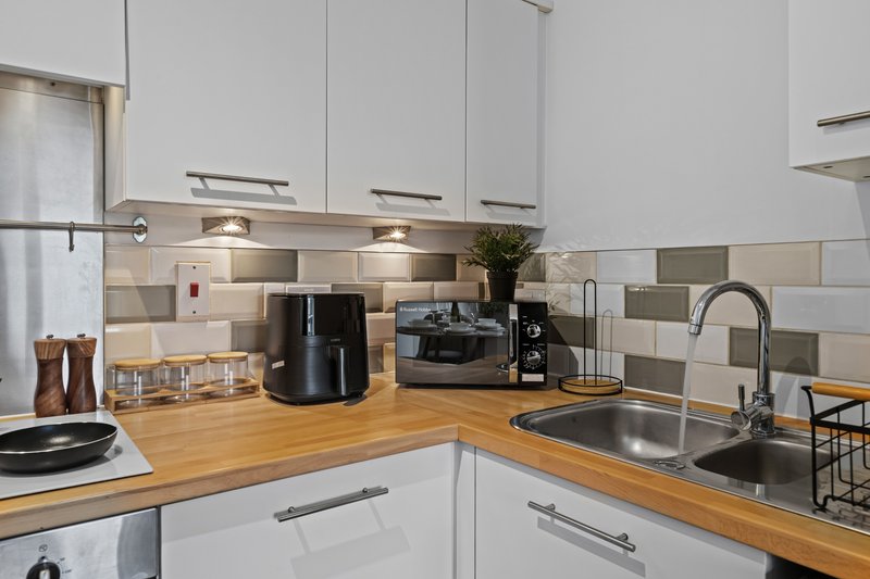 Modern white kitchen with wooden countertops, stainless steel sink, and appliances