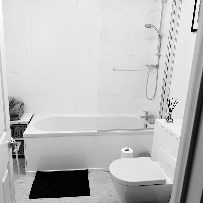 Modern bathroom with bathtub and shower, toilet and wash hand basin. Bath and hand towels provides for guests along with complimentary toiletries: shampoo, conditioners, hand wash and shower gel