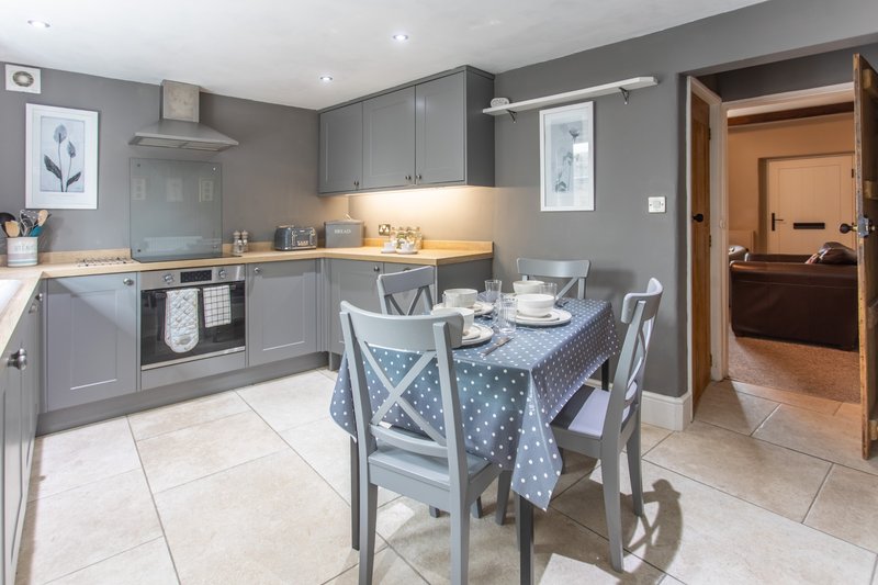 Modern kitchen-diner with gray cabinetry, dining table, chairs and open doorway to hallway