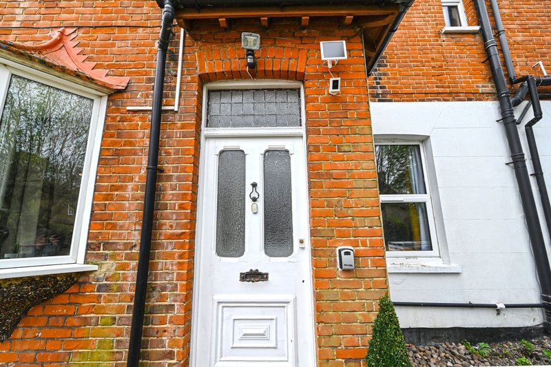 Brick terraced house exterior with white door, windows and small front garden