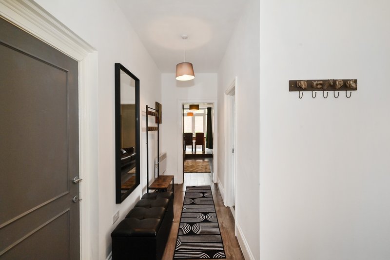 Bright hallway with grey doors, mirror, pendant light, wall hooks and runner rug