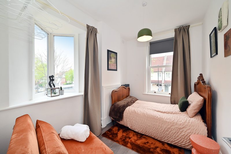 Bright bedroom with two single beds, wooden headboards, orange throws and white pillows
