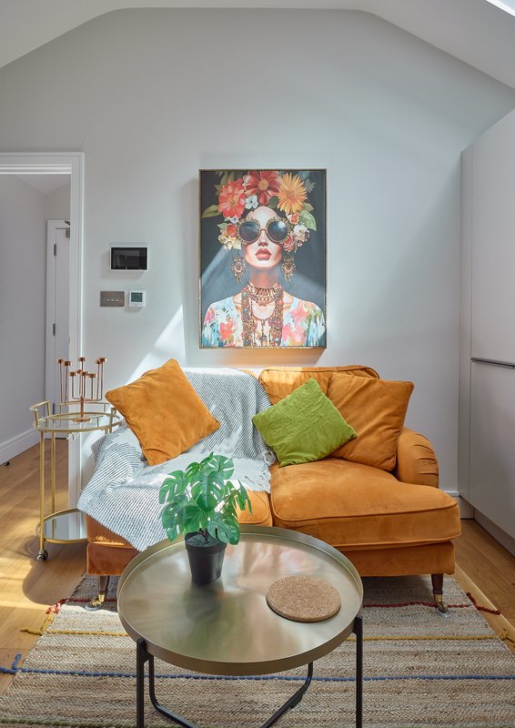 Living room with orange leather armchair, colorful cushions, round coffee table and wall art