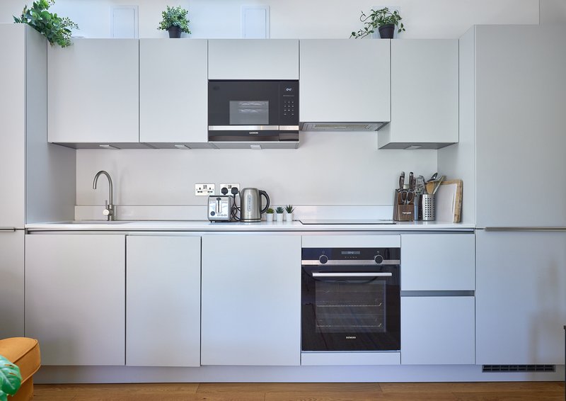 Modern kitchen with white cabinetry, black appliances, sink, and countertop accessories