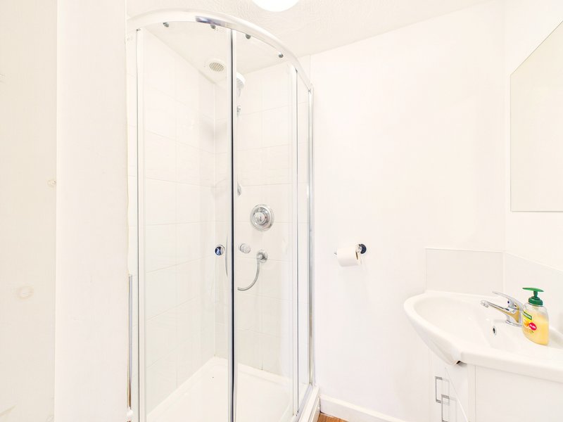 Clean modern bathroom with corner shower enclosure, white sink and chrome fixtures