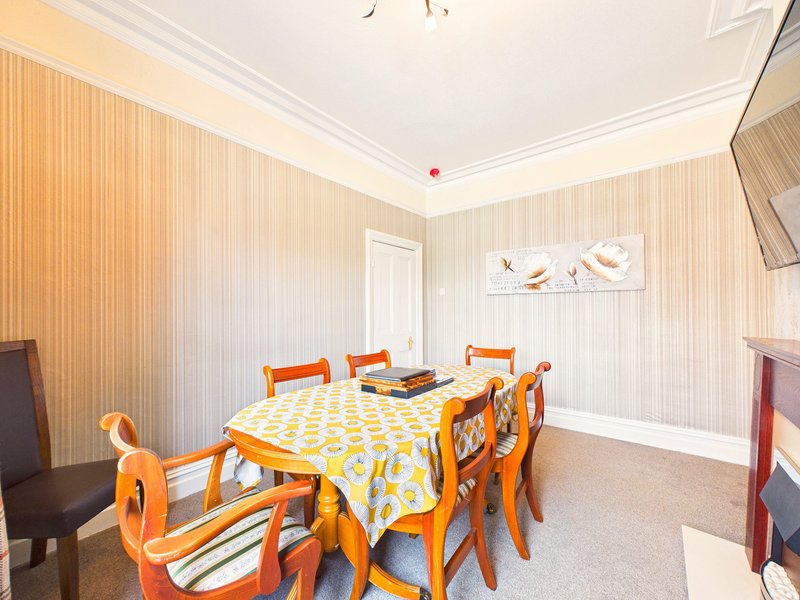 Dining room with orange chairs, yellow patterned tablecloth, and cream-colored wood paneling