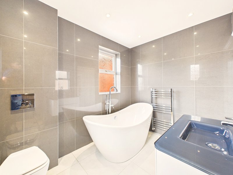 Modern bathroom with freestanding bathtub, walk-in shower, heated towel rail and window